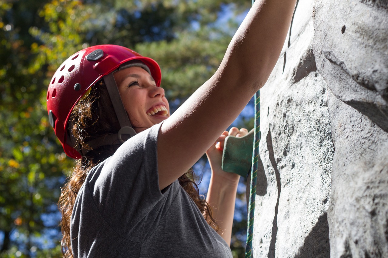 Kobieta w czerwonym kasku wspinająca się po skałach, która chce osiągnąć sukces.