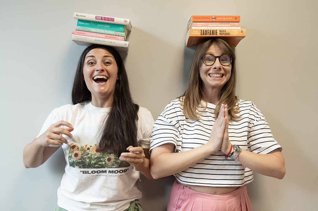Roześmiane dwie kobiety, które trzymają na głowie książki