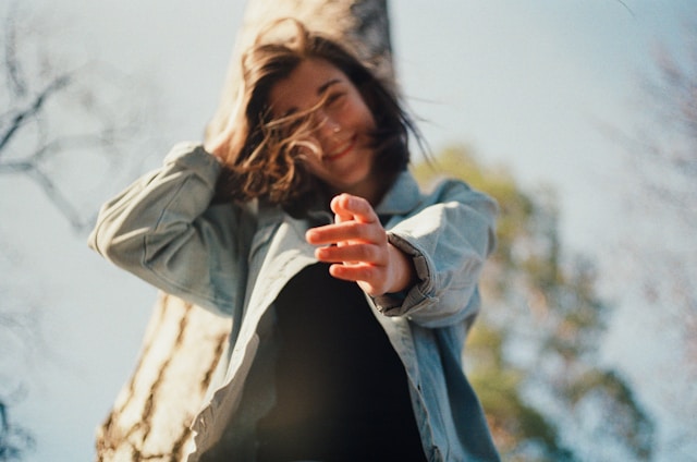 Kobieta w jeansowej kurtce uśmiecha się i pokazuje palcem w dół